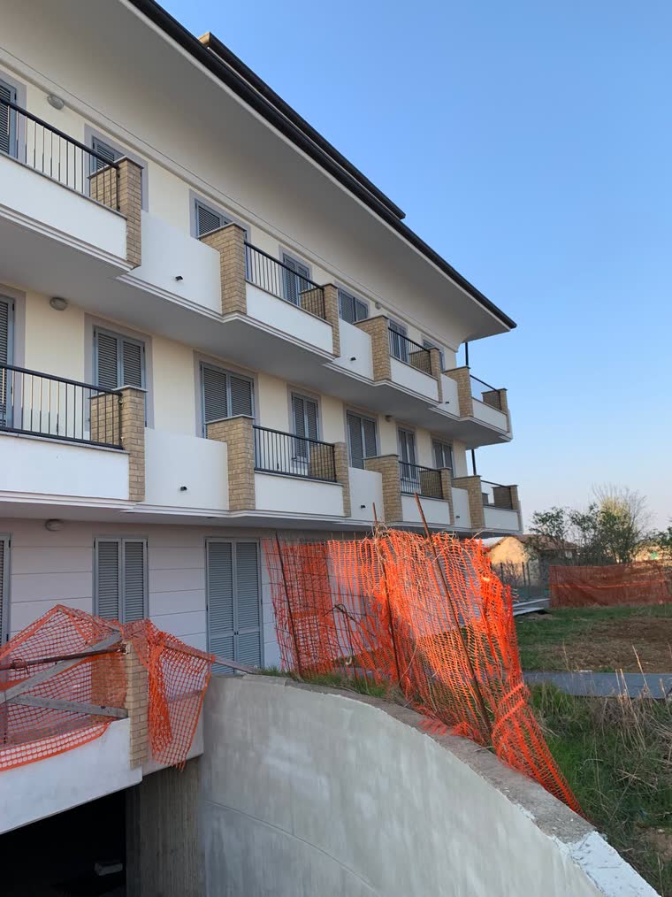 Edificio residenziale ultimato con recinzione di cantiere ancora in opera